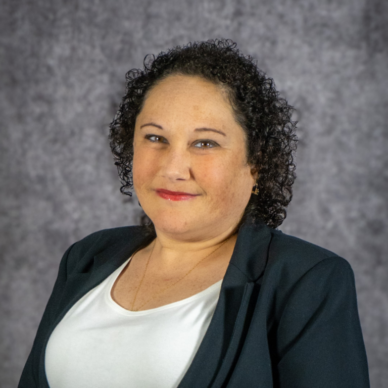Smiling woman in blazer, gray backdrop