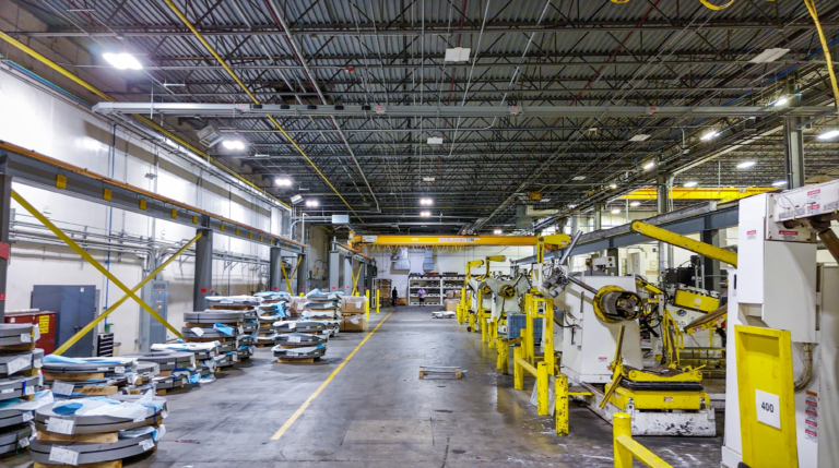 Warehouse aisle with stacked coils and machinery